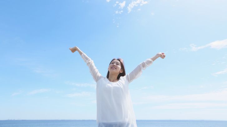 海辺で気持ちよさそうにしている女性